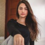 Portrait of a graceful brunette woman with long hair sitting indoors, exuding elegance and style.